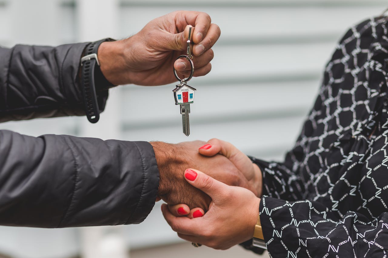 home-hero Close-up of a realtor handing over a house key to a new homeowner, symbolizing ownership and investment.